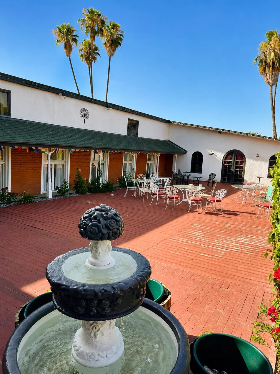The brick courtyard at The Crescent House with its tiered stone fountain and white iron cafe tables
