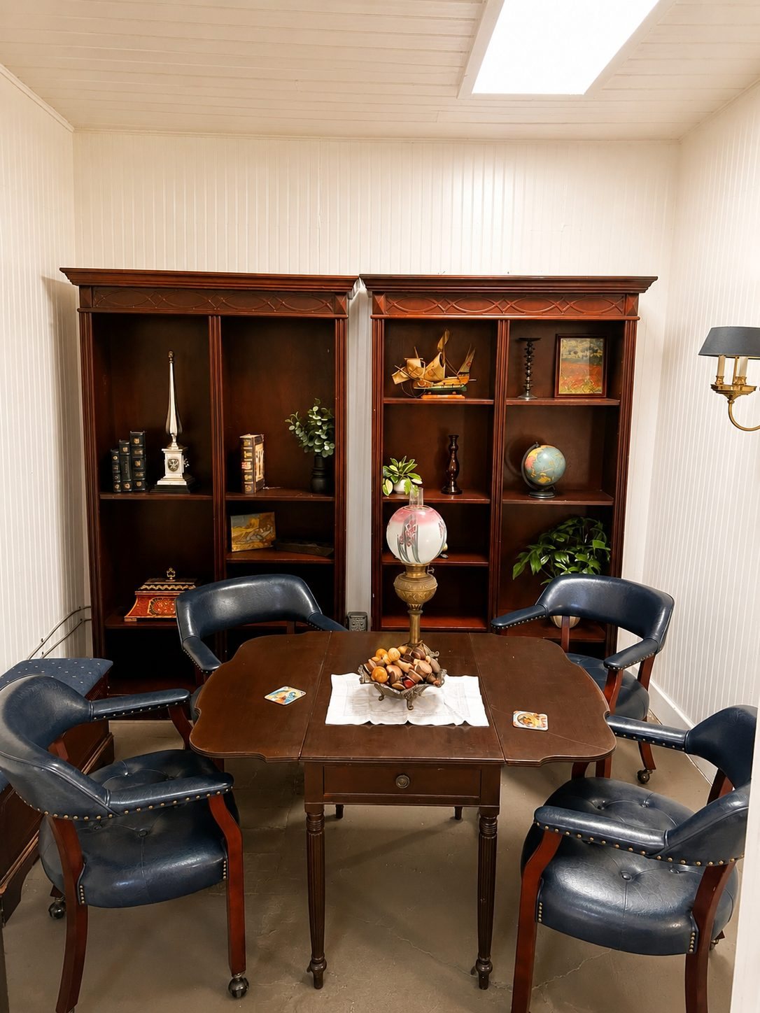 The Ferris Suite, four blue leather chairs around a drop-leaf table between two mahogany bookcases, lit by a skylight