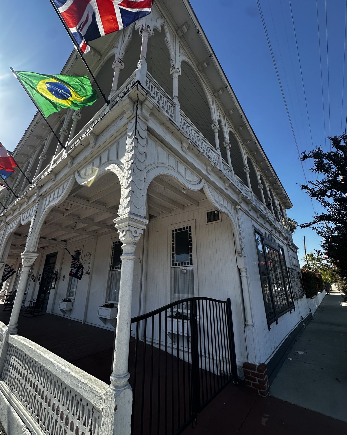 The two-story white verandas of The Crescent House flying international flags above Graham Avenue
