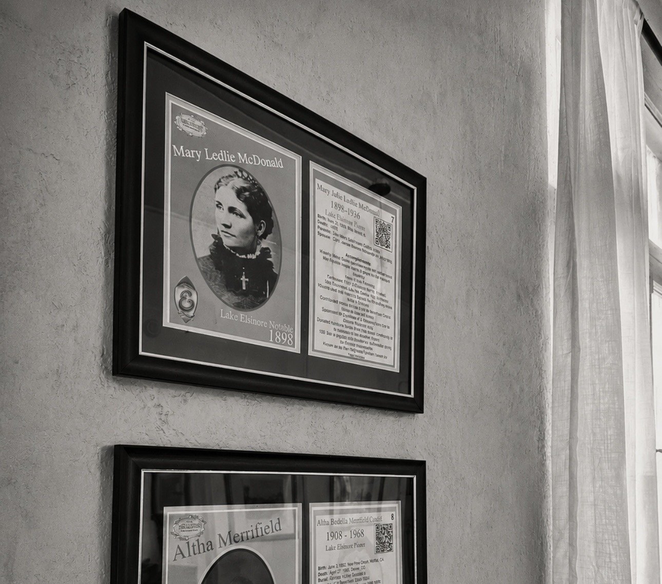 Framed Lake Elsinore Notables plaques on the wall, the upper one for Mary Ledlie McDonald with her portrait and biography, and another below for Altha Merrifield