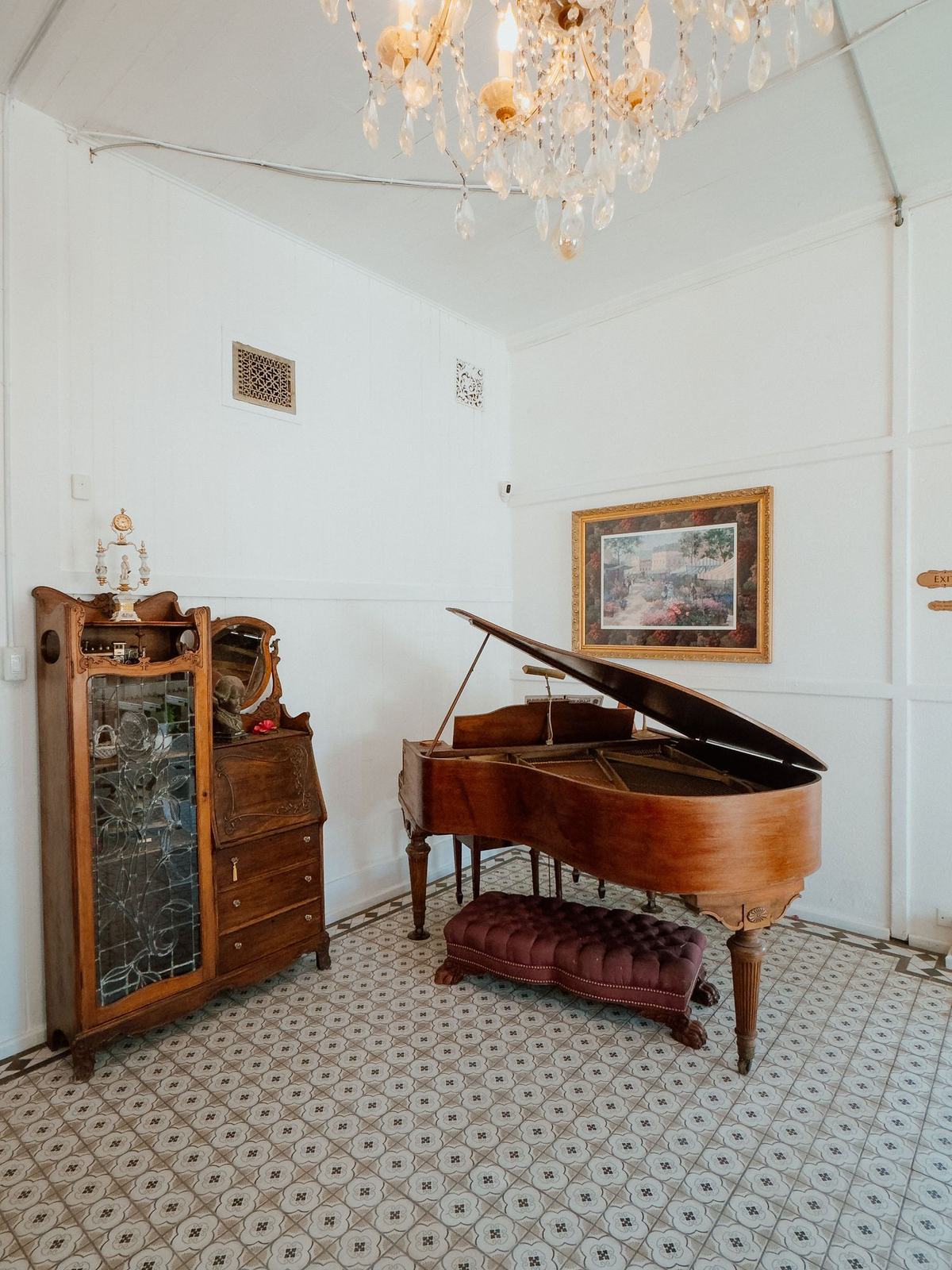 The Parlor Room, with its antique grand piano, original patterned tile, and crystal chandelier