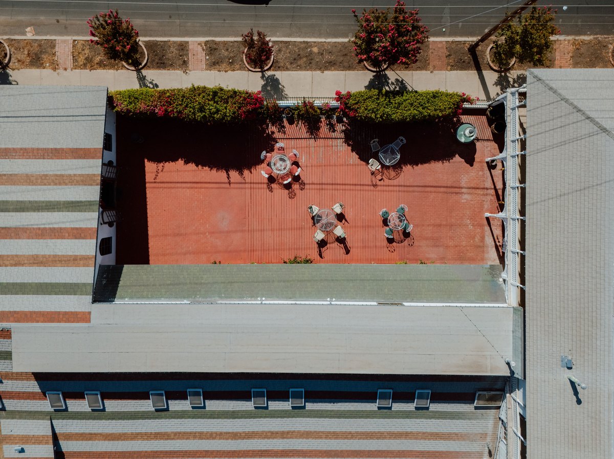 The brick courtyard from above, set with bistro tables and chairs beside the flowering trees