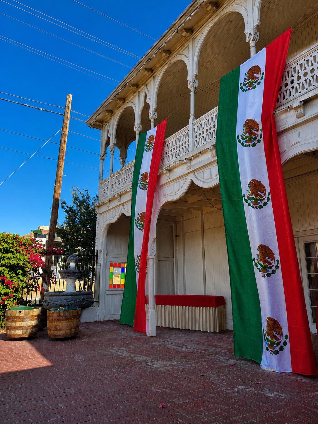 Mexican flags hanging the full height of the Victorian veranda at The Crescent House, above the brick courtyard and stone fountain