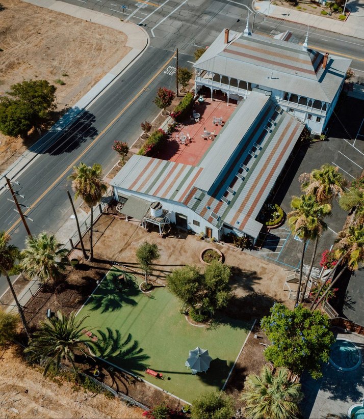 The grounds seen from above, showing the brick courtyard, the lawn, and the palms along the street