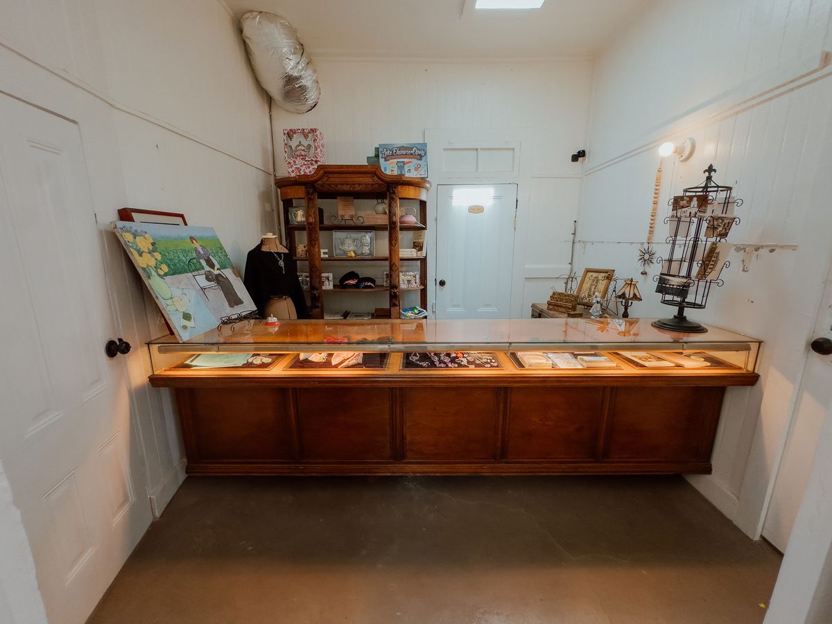 The gift shop counter, a long lit glass case with local books, jewelry, and keepsakes
