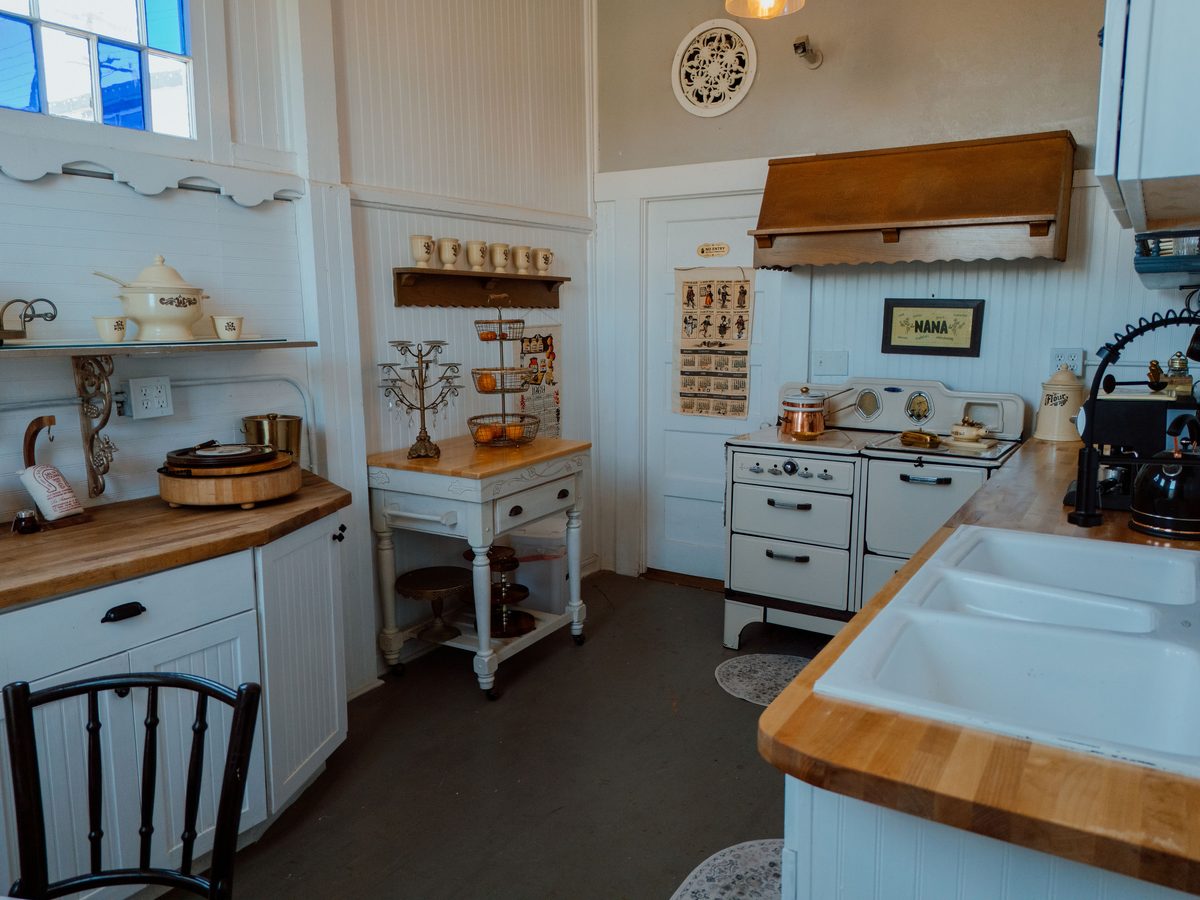 The original kitchen, with a white enamel range, butcher block counters, and a deep farmhouse sink