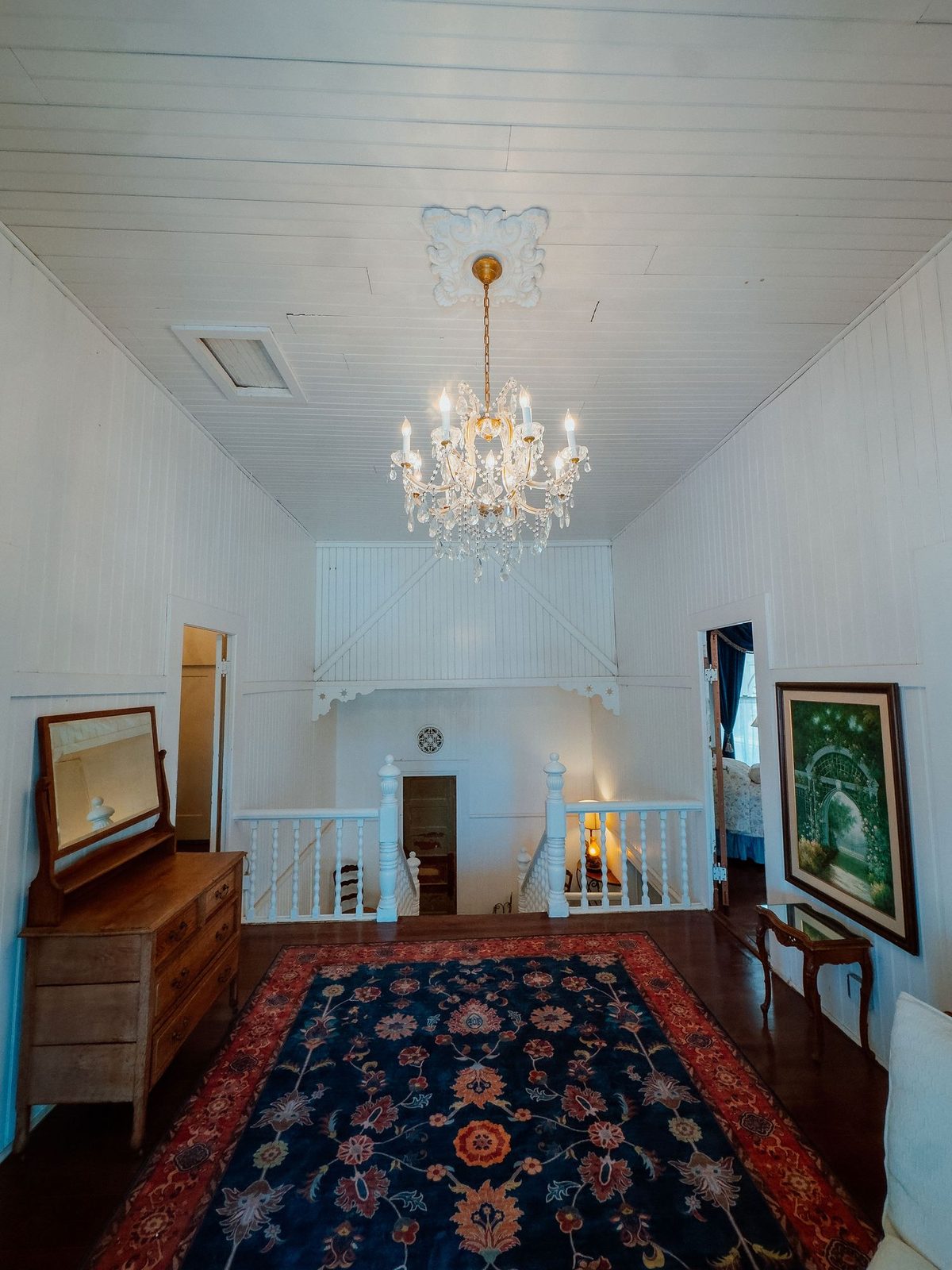 The upstairs landing, with its crystal chandelier and patterned rug