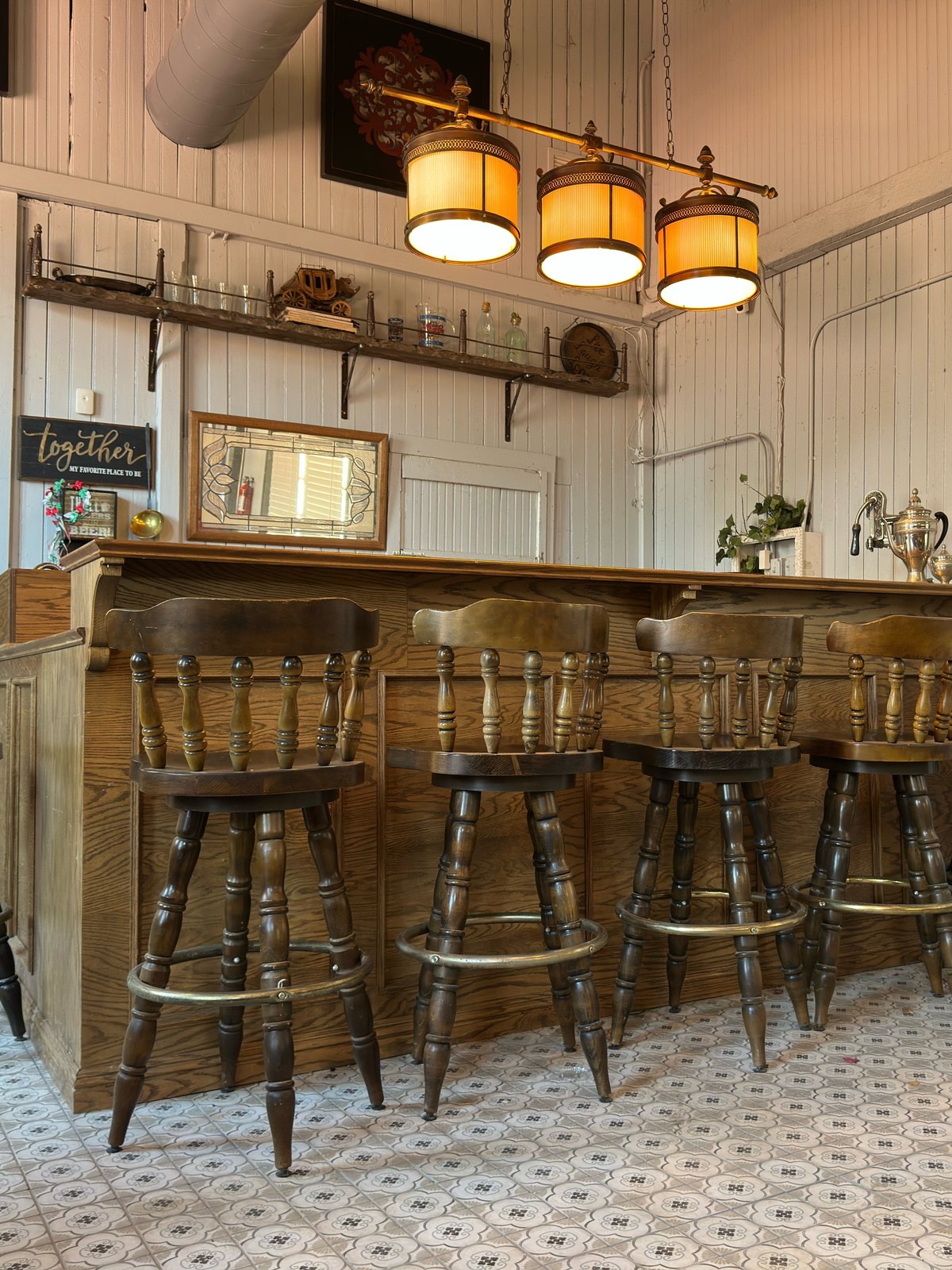The bar inside The Library Speakeasy, with its wooden stools and patterned tile floor