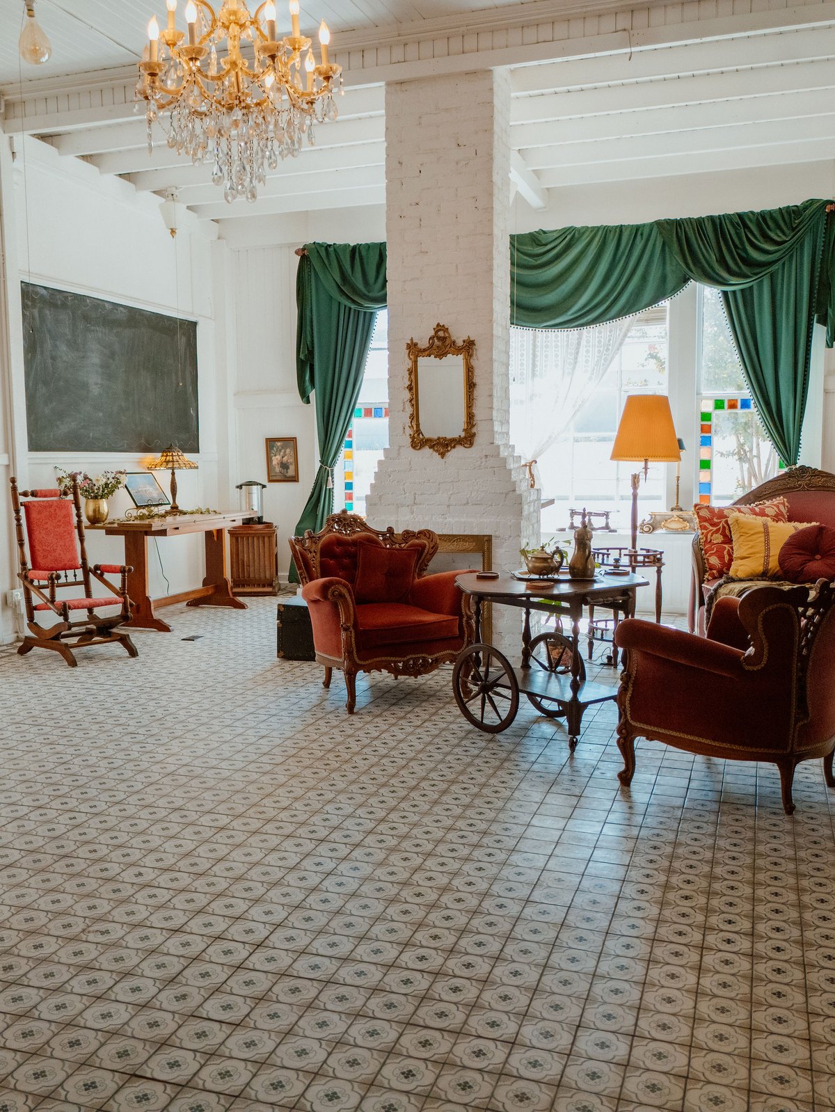 The Parlor Room, with its original patterned tile floor, green drapes, and Victorian seating